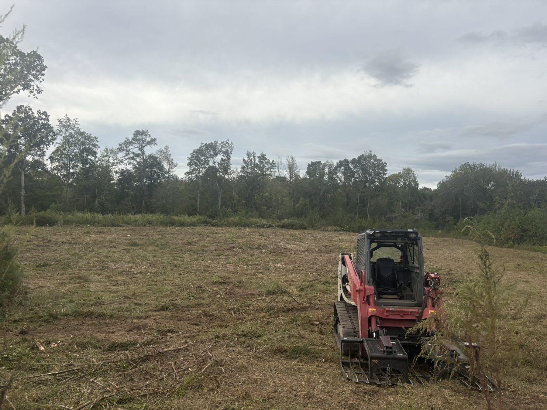 Red Takeuchi mulcher mid-job in a cleared field